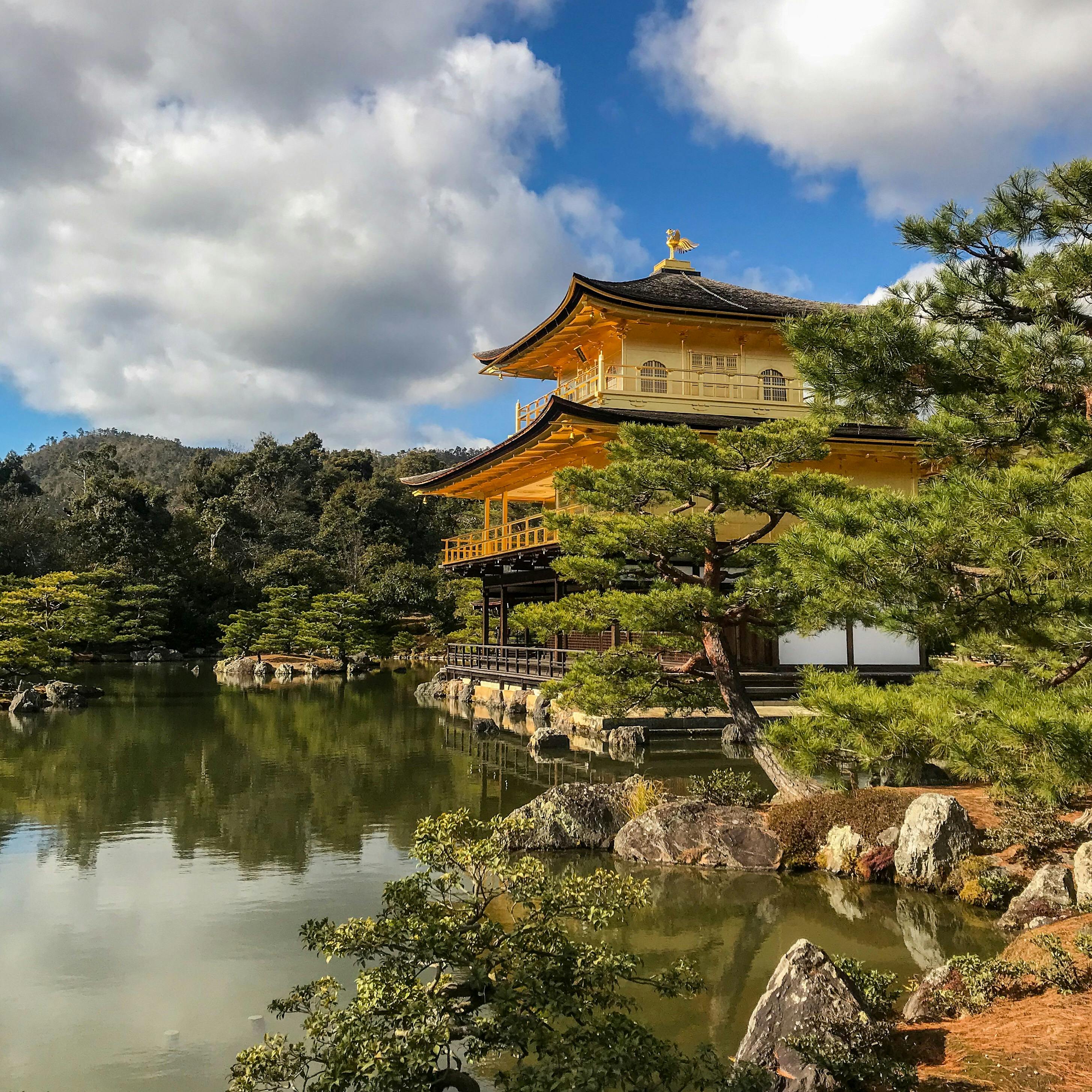 Kinkaku-ji Golden Pavilion reflected in the lake surrounded by pine trees in Kyoto