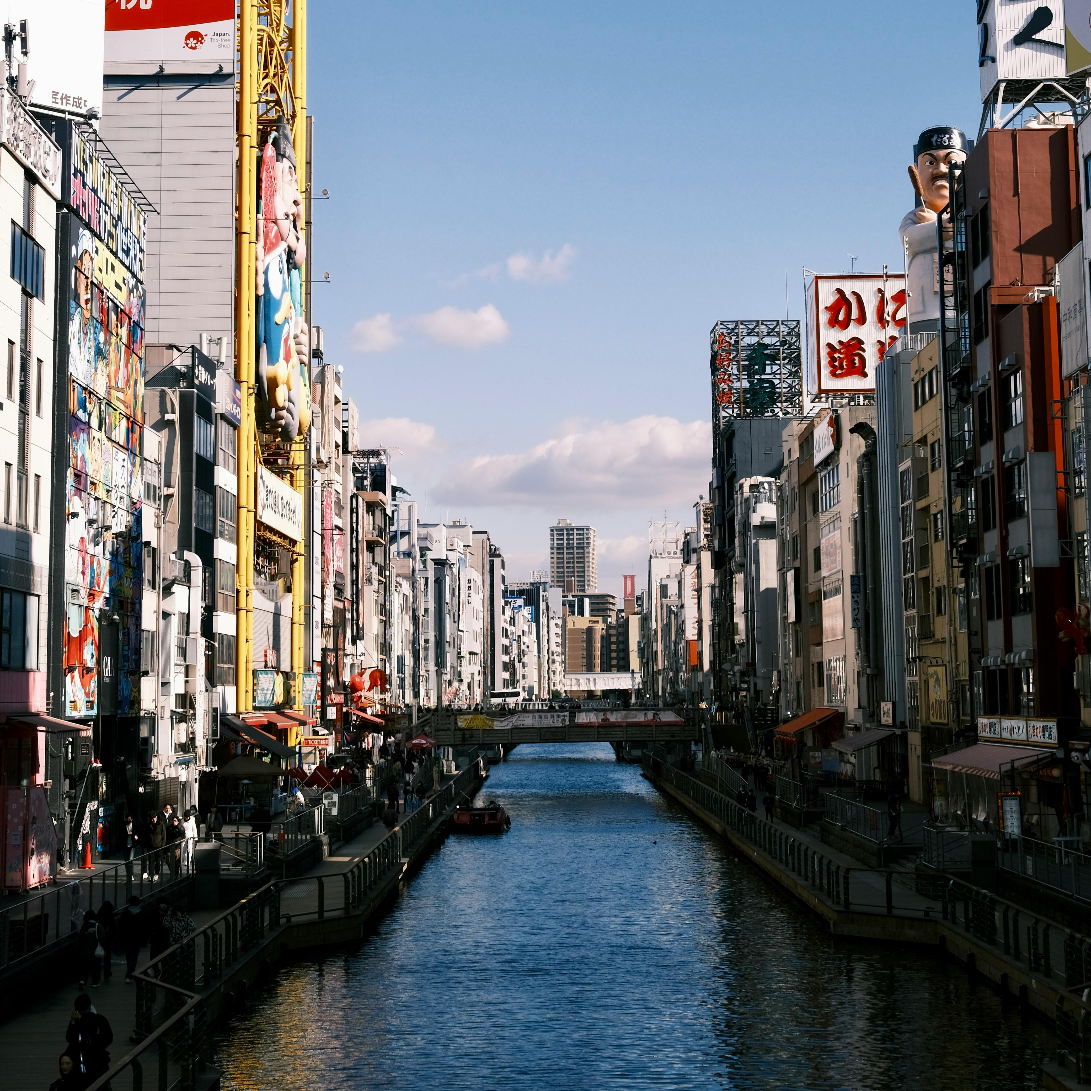 Dotonbori Canal in Osaka lined with restaurants and neon lights under a vibrant evening sky