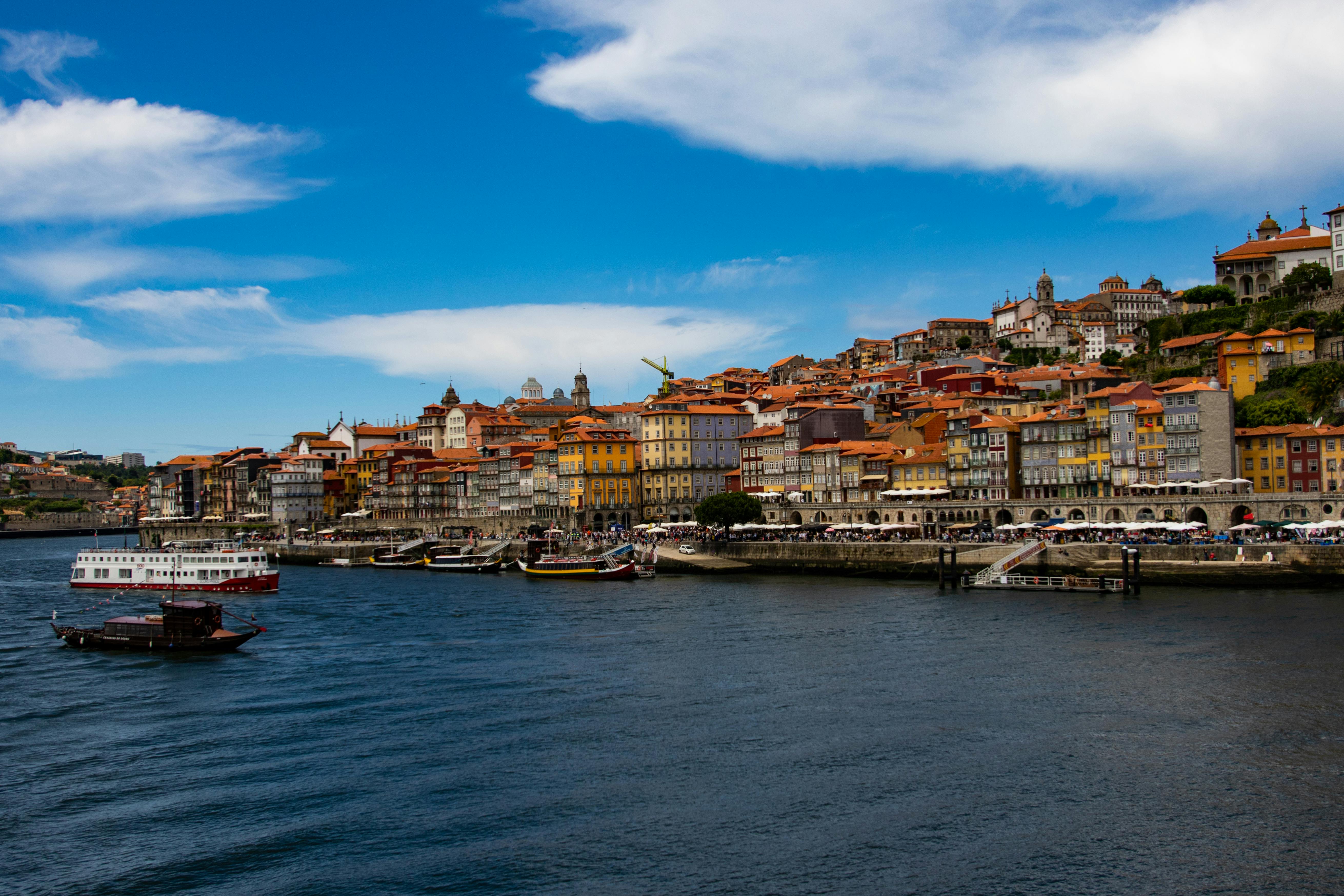 Colorful houses and boats along the Douro River in Porto under a clear blue sky